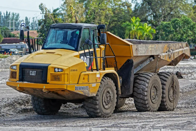 Kloubový terénní damper Caterpillar na staveništi